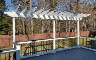 white pergola on top of a gray deck with white and black railing